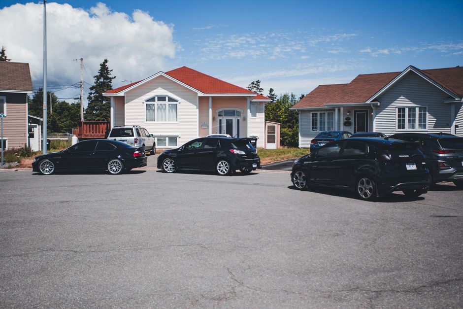 A residential street scene captured during daytime with a white van from Man with Van Sudbury parked near a house, preparing for a home relocation. The van is positioned on the road, adjacent to a bla